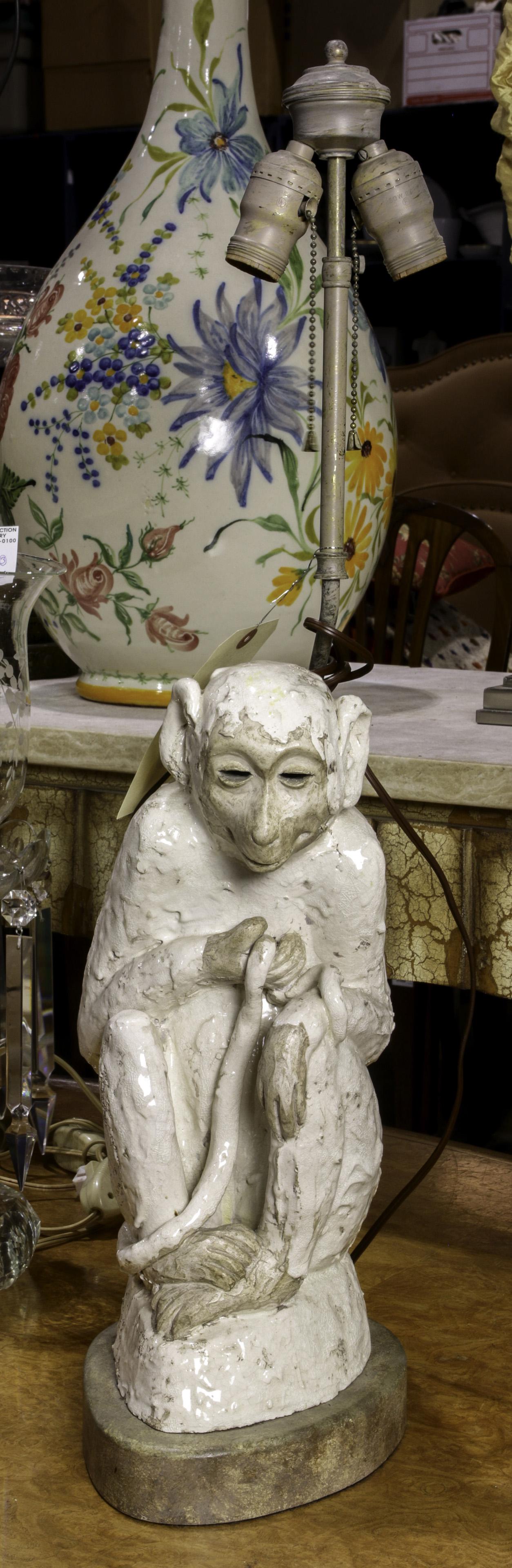 A tin glazed monkey form sculpture mounted as a lamp: A tin glazed monkey form sculpture mounted as a lamp, depicted seated and holding its tale, sculpture 17"h