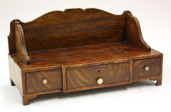 Edwardian desk top bookshelf: Edwardian desk top bookshelf having a breakfront over three drawers with flame mahogany veneer and raised on block feet 10''h x 19''w x 8''d