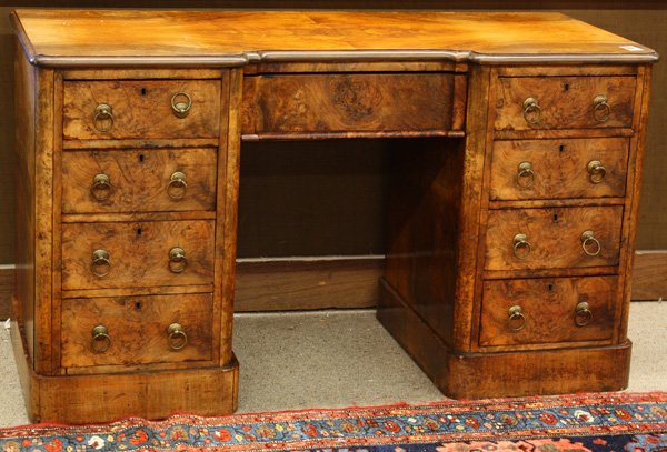 Edwardian walnut-burl kneehole desk: Edwardian walnut-burl kneehole desk, the butterfly veneered, shaped top above a central drawer flanked by four drawers on each side, the entire finished case raised on a molded base, 29''h x 50''w x 2