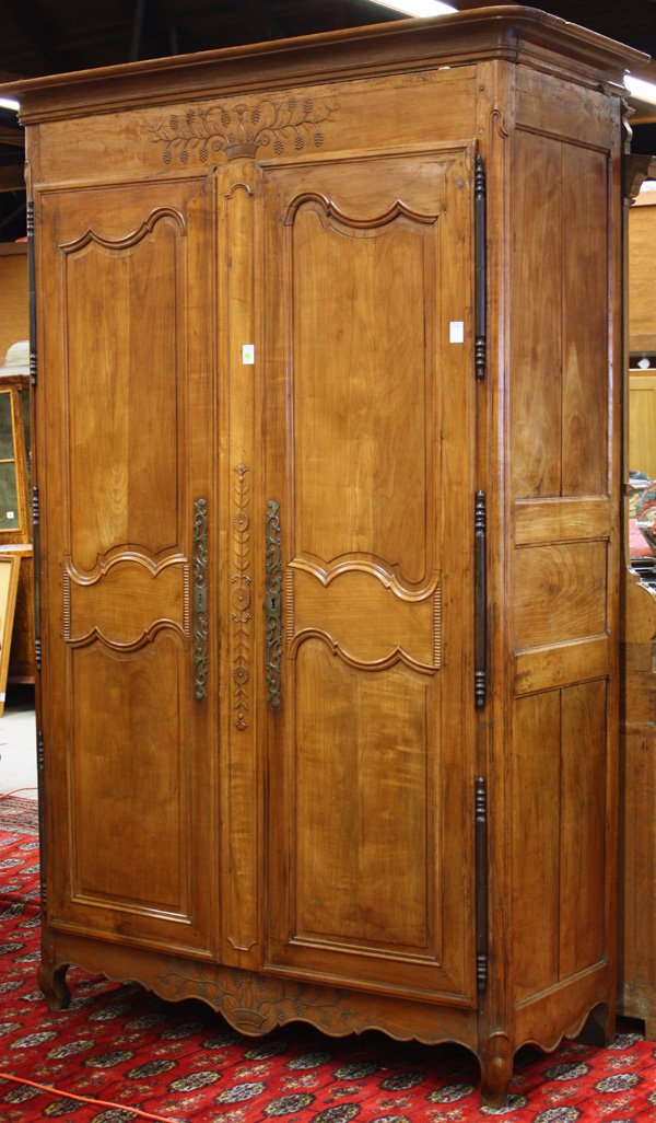 Louis XV provincial carved cherry armoire: Louis XV provincial carved cherry armoire, circa 1750, moulded flat cornice above double doors having low relief flower basket and floral carvings raising on short cabriole legs, 96''h x 62''w x 26''d