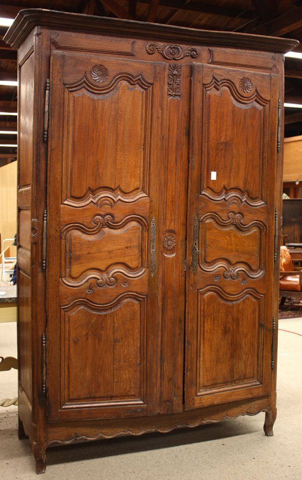 Louis XV Provincial oak armoire: Louis XV Provincial oak armoire, circa 1750, having flat molded cornice, centered with floral relief, pinwheel carved and molded doors, the whole rising on short cabriole legs, 94''h x 67''w x 26''d (