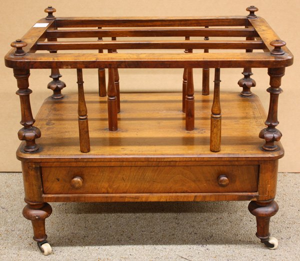 Edwardian walnut three section canterbury: Edwardian walnut three section canterbury, the finial capped top with walnut burl veneer and turned column supports, above a single drawer and raised on turned legs with casters 19''h x 23''w x 17''d