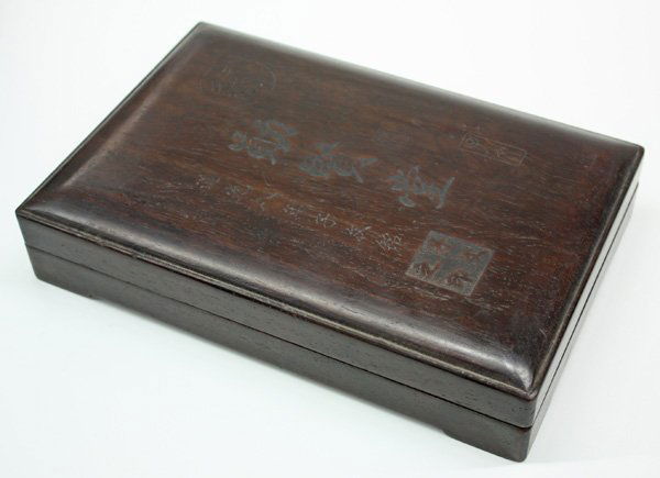 Chinese Inkstone, Hardwood Box: Chinese rectangular form inkstone, with the cartouche 'bai zhi zheng ming' to the right of an inscription, all above a shallow well, reversed by a pair of seven-character couplets and reading '[zhou]