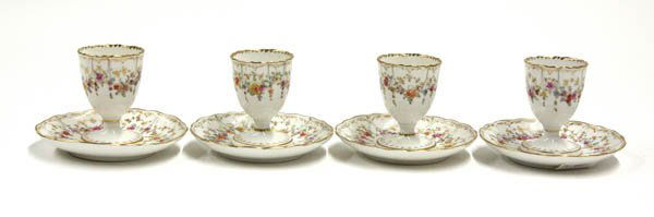 Porcelain polychrome and gilt egg cups: (lot of 4) Porcelain polychrome and gilt egg cups, each with floral swag detailon a white ground, the saucer with gilt accents and signed with cancelled Meissen blue cross hatch underglaze mark 3''h x