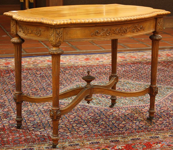Neoclassical style library table: Neoclassical style library table circa 1900, the top with a finger roll edge above a conforming apron having applied foliate carvings and acanthus detail, raised on fluted legs with a finial capped X 