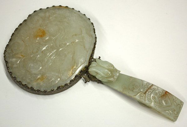 Chinese Jade and Metal Hand Mirror: Chinese jade and silvered metal hand mirror, the oval head backed by a pale-green jade plaque of ruyi shape and carved with fruiting peach sprays, portions of the design incorporating faint russet inc