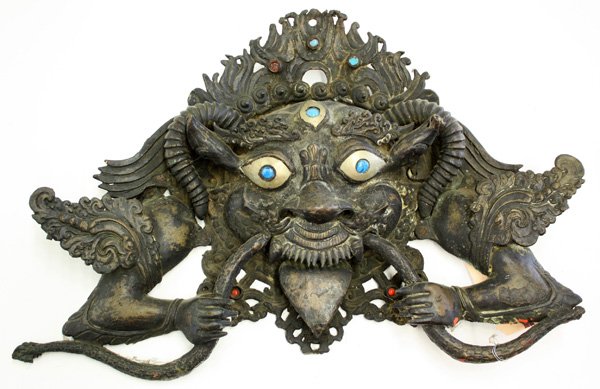 Nepalese Architectural Ornament: Nepalese architectural ornament fashioned as kirtimukha, the fierce Hindu demon face with monstrous features and bulging eyes inlaid with blue glass, usually placed over the lintel or gateway of Hindu