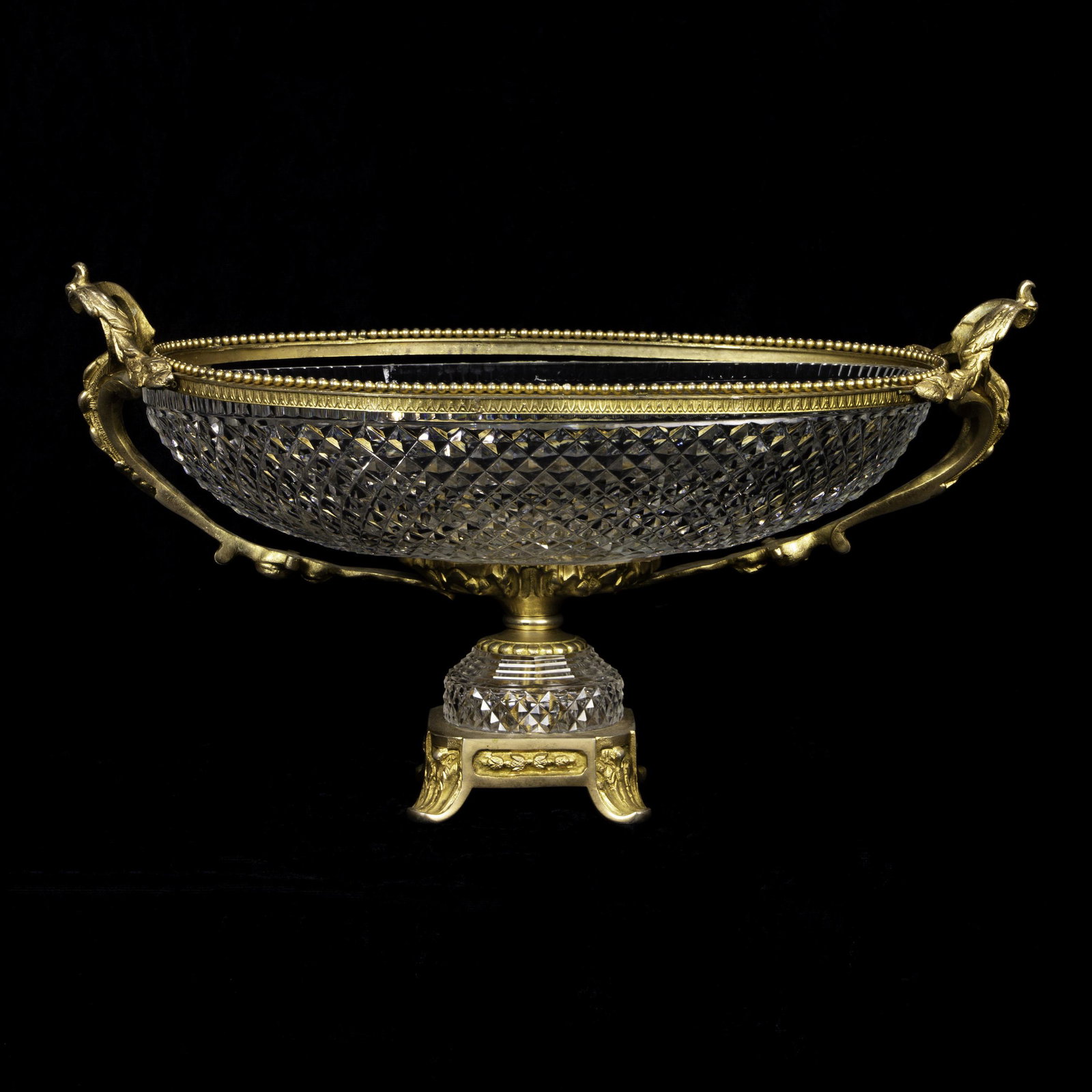 A Continental gilt mounted crystal centerpiece: A Continental gilt mounted crystal centerpiece, the oval form with twin gilt auricular mounts, and rising on a footed base, 9"h x 17"w