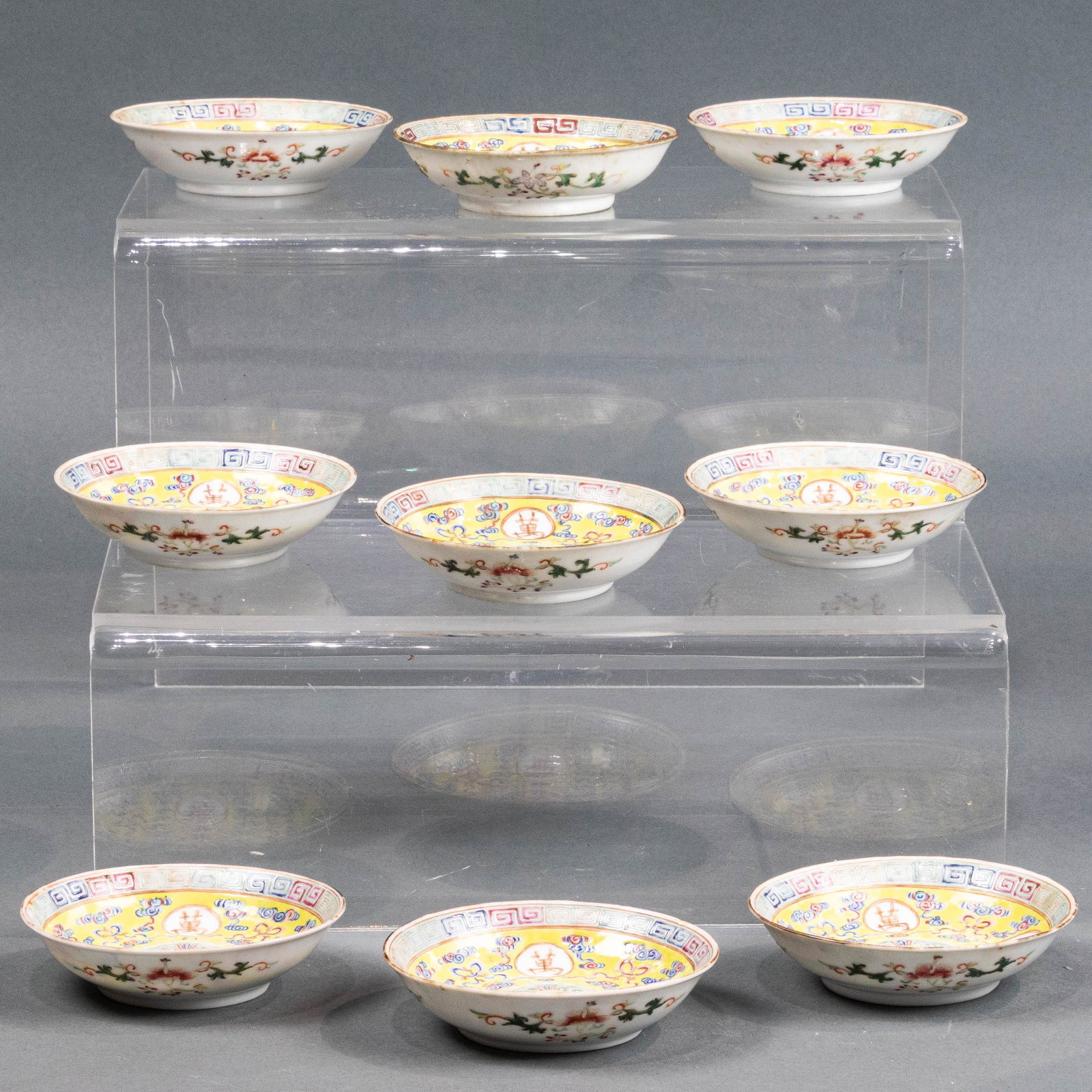 (lot of 9) Chinese famille rose saucer dishes: (lot of 9) Chinese famille rose saucer dishes, each interior well centering a Shou medallion surrounded by four gilt decorated "Wan Shou Wu Jiang" medallions, all against a yellow ground with scrollin