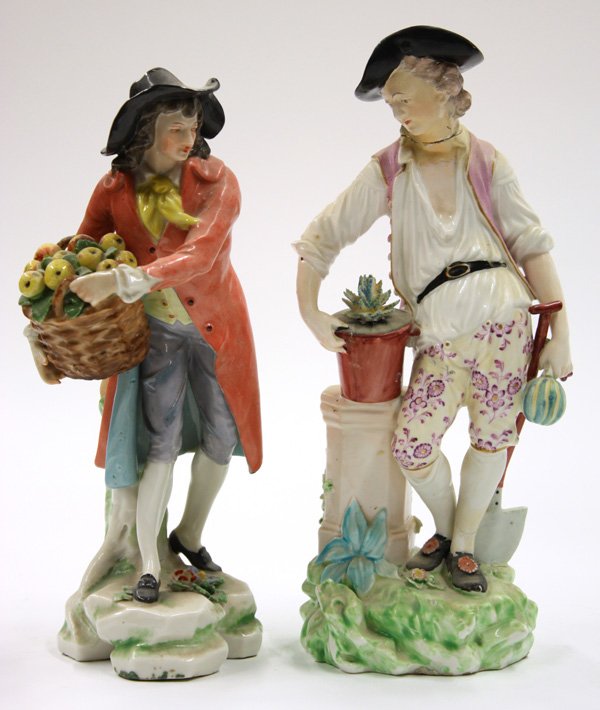 German porcelain figures of farming men: Two German porcelain figures of farming men in 18th century dress, one having a black hat and red coat, holding a basket of apples, impressed with an underglazed crowned N, and Germany, 9''h, the figu