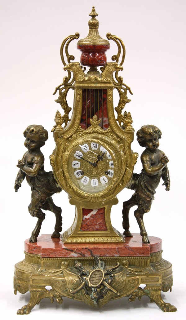 German gilt metal and marble mantle clock: German gilt metal and marble mantle clock, the finial capped case with raised, painted porcelain roman numeral marks flanked between two hoofed putti, and raised on a marble base with swag and tassel 