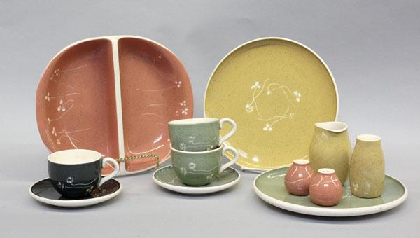 Russel Wright dinnerware: (lot of 229) Three shelves displaying Russel Wright ''White Clover'' pattern assembled table services in Golden Spice, Meadow Green, Charcoal, and Coral Sand