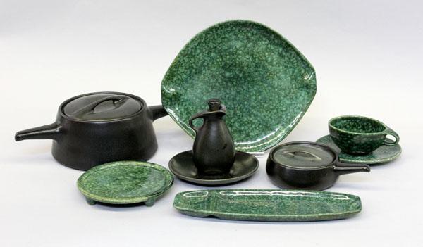 Roseville Raymor tableware: (lot of 106) Two shelves showing Roseville Raymor modern stoneware tablewares in avocado green and frog skin green including dinner, salad, and bread plates, cups & saucers, trivets, bean pots, handle