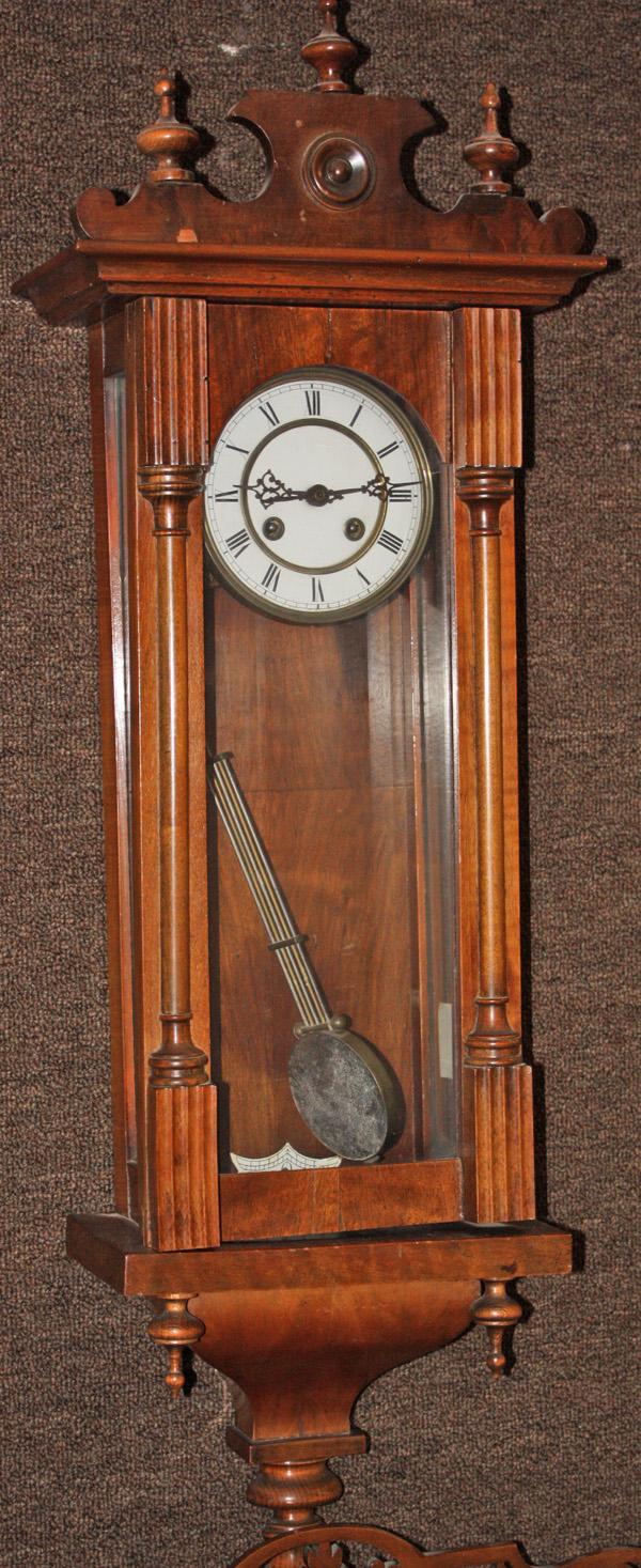German Regulator Clock: German regulator clock, the mahogany case with a carved crest above the single door, opening to reveal a paint decorated enamel face, the pendulum with a script RA, overall 38''h x 10''w x 5.5''d
