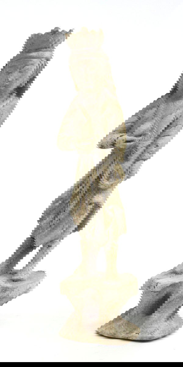 Chinese Attendant Figure: Chinese figure of an attendant, Sui/Tang style, standing in thick robes and heavy boots on a rocky plinth, one hand held to the front with a sacred jewel, the serene face framed by a an ornate floral