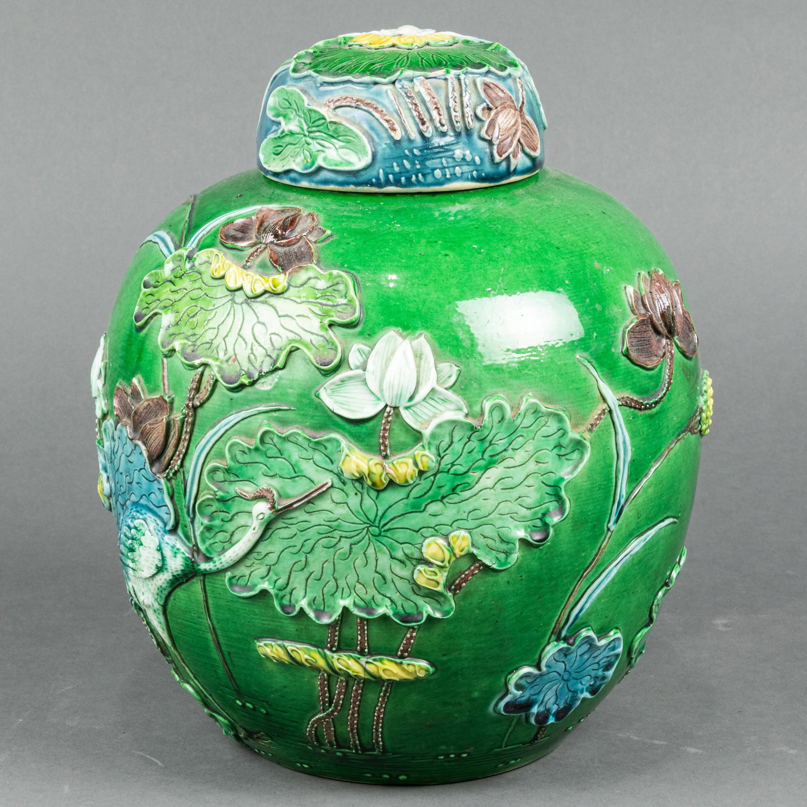 Chinese famille verte vase: Chinese famille verte vase, the body covered in overall rich green glaze, molded with a crane amongst lotus bloom and leaves, the lid covered in dark blue glaze, molded with lotus bloom, 10"h.