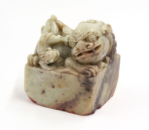 Chinese Soapstone Fu-Lion Seal: Chinese carved soapstone seal, featuring a humorous fu-lion playing with its young above a rectangular plinth, the gray-green matrix mottled with russet and brown inclusions, bottom carved with two ch