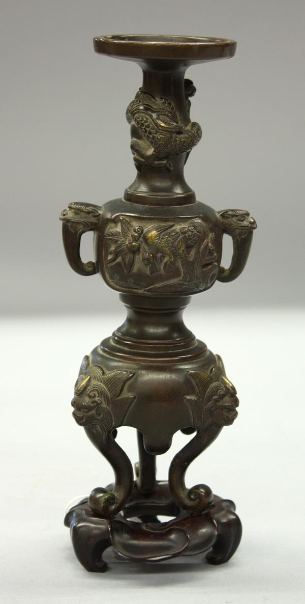 Japanese Copper Alloy Candle Holder: Japanese patinated copper alloy candle holder, shaped as a handled censer with bird-and-flower reserves above a high pedestal base and cabriole legs, with wood stand, 7.6''h