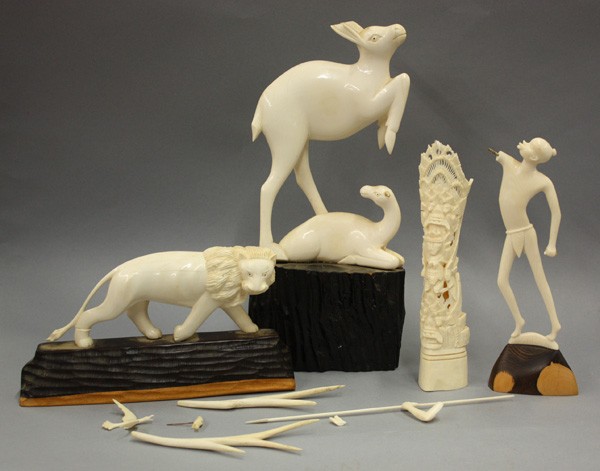 carved ivory lion, deer, warrior, totem pole: (lot of 4) Carved ivory consisting of a lion mounted to a carved wood plinth, 4.75'' x 9''; totem pole with figures, 8''; deer and its doe mounted to a wood base, 17''h (doe lacking antlers); and an A