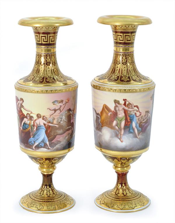 Pair of Royal Vienna Urns signed Wagner: Pair of hand painted Royal Vienna urns, each signed Wagner, having raised gilt and enamel work on a burgundy lustre ground, the mythological frieze, one depicting Helios, and one depicting Aurora, enc