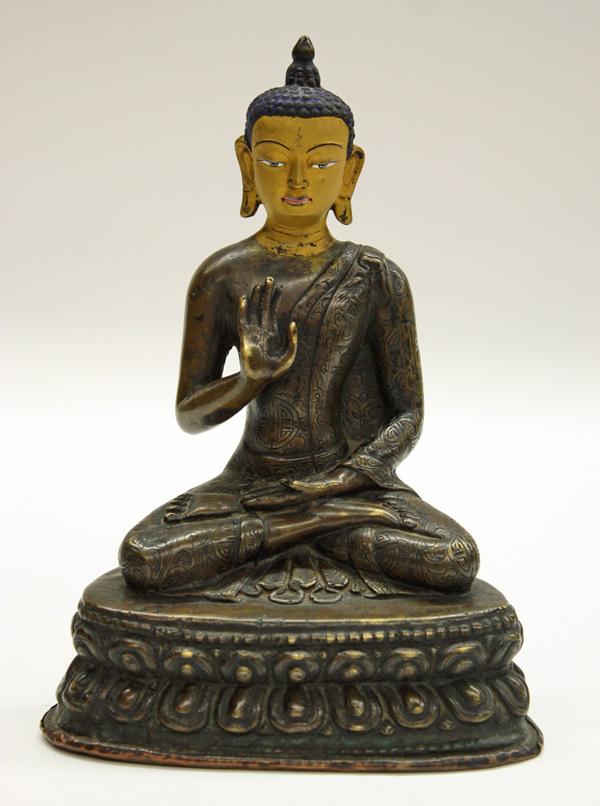 Nepalese Bronze Buddha Figure, 19th Century: Nepalese cast bronze figure of a Buddha, 19th century, seated dhyanasana on a triangular double-lotus base, the slender figure clothed in brocade-patterned monastic robes and displaying the 'fear-not 