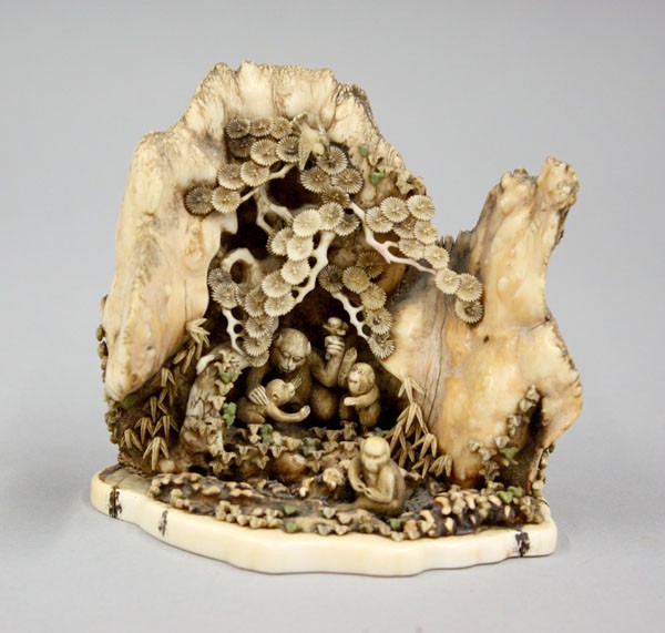 Japanese Ivory Okimono, Monkeys: Japanese ivory carving (okimono), well carved and incised as a troop of four monkeys cavorting in a grotto framed by a large pine growing near leafy bamboo and climbing ivy vines extending to the back