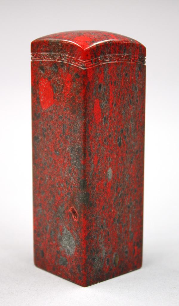 Chinese Red Soapstone Seal: Chinese red colored soapstone seal, the rectangular shaft with a slightly rounded top above a key fret band, base uncarved, the vibrant red matrix mottled with dark flecks, 3.6''h