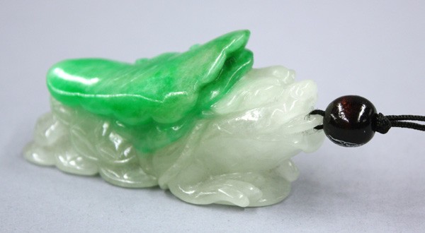 Chinese Jadeite Toggle: Chinese carved jadeite toggle, fashioned with a leonine-headed three legged toad of celadon hue with a chain of cash coins hiding beneath a bright green colored ruyi head, 2.25''h