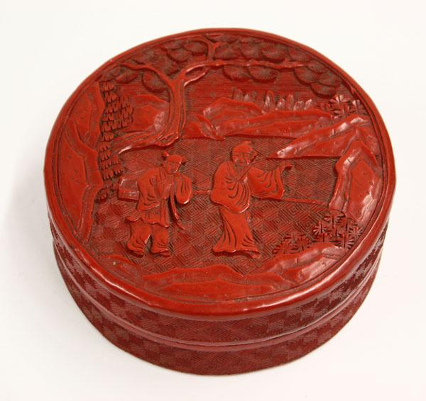 Chinese Cinnabar Lacquer Box: Chinese carved cinnabar lacquered circular box, early 20th century, the lid featuring a scholar and attendant in landscape under stylized pine and set against patterned geometric ground, the exterior
