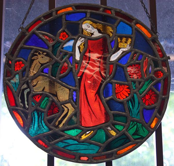 Leaded glass panels: (lot of 2) Two continental leaded and stained glass panels, one depicting a maiden in a forest interior, set in acircular frame 12''w, together with a German ecclesiastical scene with ribbon form text