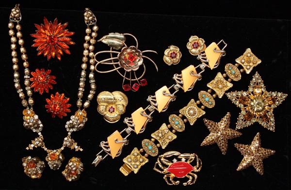 Lot of fashion jewelry: (lot of 12) Pieces of costume jewelry including; Judy Lee red-orange flower form brooch and clip-on earring set, a Jomaz gold tone with clear and ruby red rhinestone accent brooch and clip-on earring