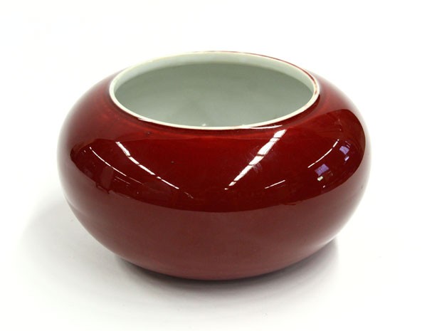 Chinese Ox-blood Porcelain Bowl: Chinese ox blood glazed porcelain bowl, the compressed globular body of a red hue to the exterior with slight pooling of glaze encircling the wide mouth rim, the interior and recessed base coated with