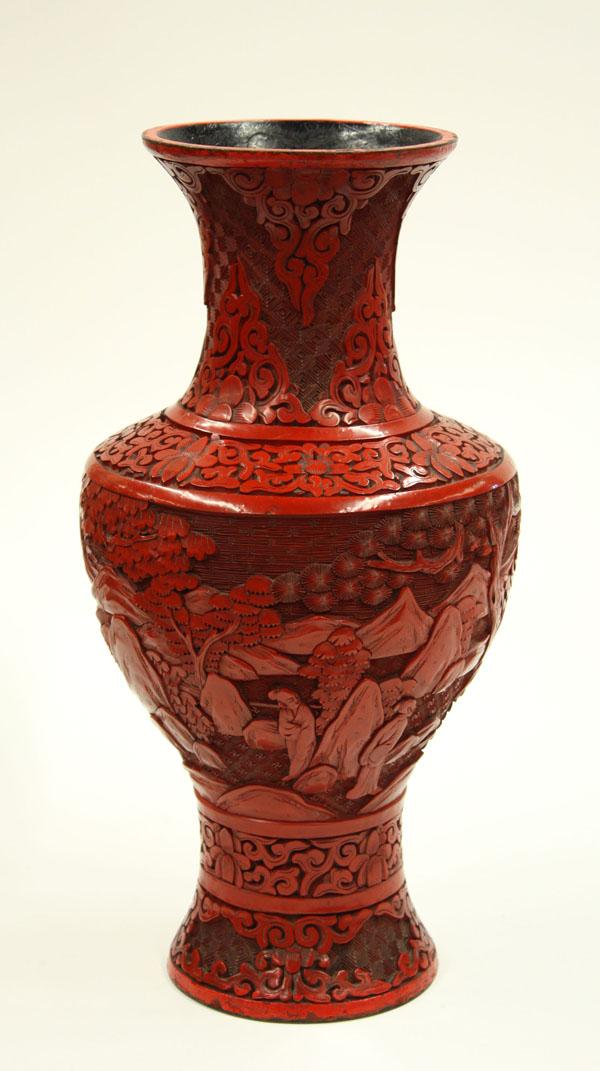 Chinese Cinnabar Lacquer Vase: Chinese carved cinnabar lacquer baluster vase, early 20th century, featuring scholars in a landscape under gnarling pines, bracketed by scrolling floral bands to the neck and base (base retouched), 11
