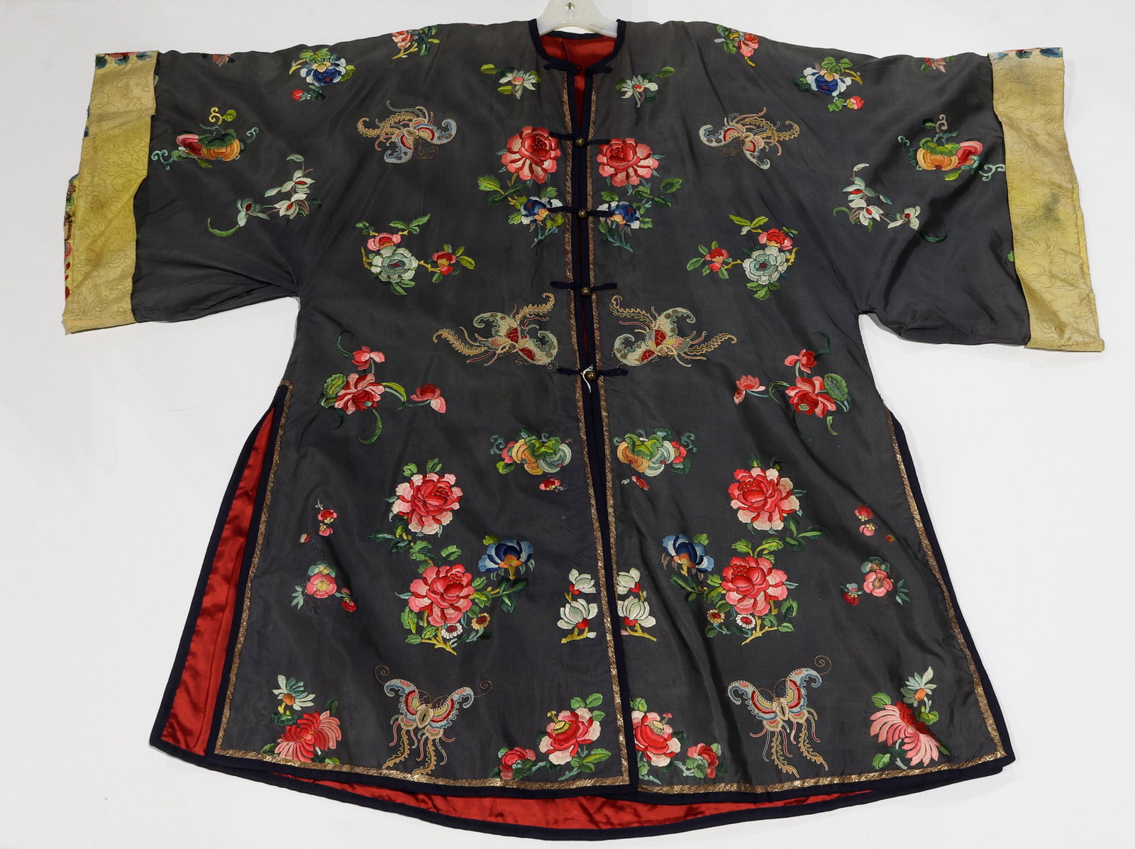 Chinese embrodered silk robe: Chinese embrodered silk robe, featuring butterflies executed in knot stitch along with various embroidered floral and fruit sprays, all set against a gray ground, 43" x 56".