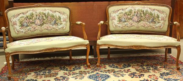 Louis XV style upholstered walnut settees: (Lot of 2) Pair of Louis XV style upholstered walnut settees, each upholstered with needlepoint fabric depicting a classical romantic scene and raised on cabriole legs, each 38.5''h x 48''w x 22.5''d