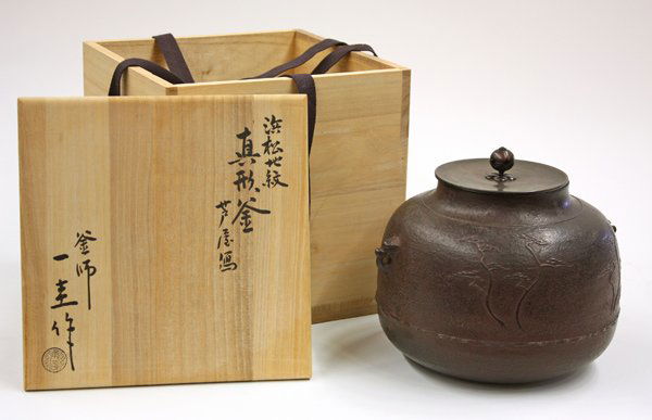Japanese Iron Kettle, Kakutani Ikkei, Signed Box: Japanese iron kettle by Kakutani Ikkei (1904-1999) (appointed Living National Treasure in 1978), of compressed ovoid shape cast in low relief with pines along a seashore, a pair of small animal-headed
