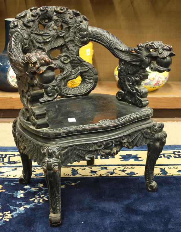 Japanese Export Dragon Chair: Japanese ebonized export wooden chair, the back elaborated carved with a writhing dragon emerging from cloud scrolls and bracketed by dragon-form arms, each mythical beast with a sacred jewel in its m