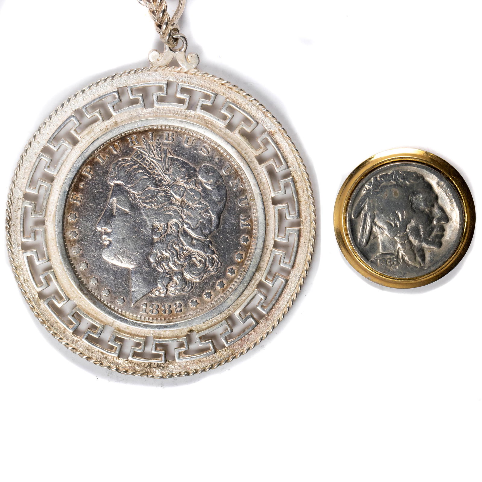 A (lot of 2) coin jewelry items: a 1882 Morgan dollar: A (lot of 2) coin jewelry items: a 1882 Morgan dollar mounted in a Greek key bezel surround mounted on a silver link necklace; en suite with a 1936 Buffalo nickel mounted as a clip earring.