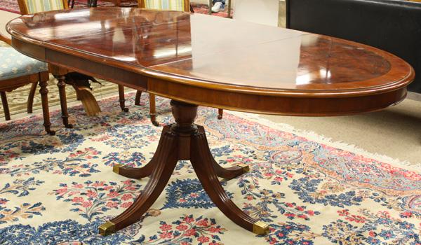 Regency style mahogany dining table: Regency style mahogany dining table, the oval top with band and string inlay above a turned standard and rising on outswept feet terminating in brass caps, 29''h x 50''w (72''extended) x 40''d (one 22