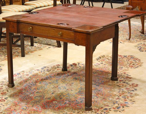 George III Chippendale card table: George III Chippendale mahogany card table circa 1770, having a shaped single board top opening to reveal a later playing surface surrounded by candle nothces and game pockets, rising on square canted