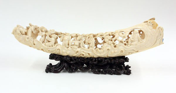 Chinese Pierced Ivory Tusk, Figues: Chinese reticulated ivory tusk, 20th century, featuring immortals, ascetics, scholars and other figures in various elegant pursuits framed by a gnarled pine tree pierced to either side (losses and rep