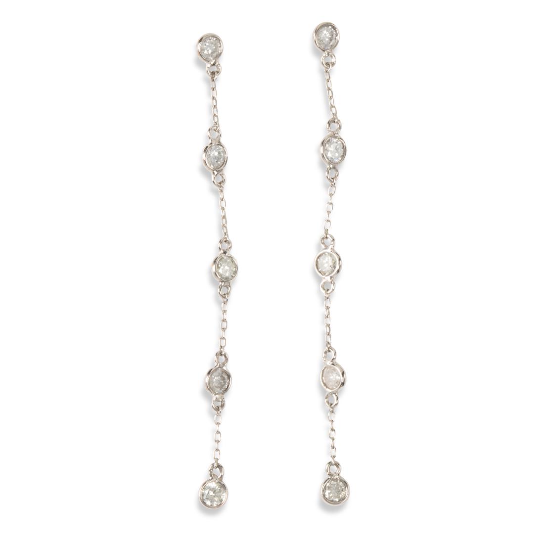 A pair of diamond and fourteen karat white gold: A pair of diamond and fourteen karat white gold earrings each designed as a line of spectacle-set round brilliant-cut diamonds on cable link chain. 0.8 dwt; length: 2 in