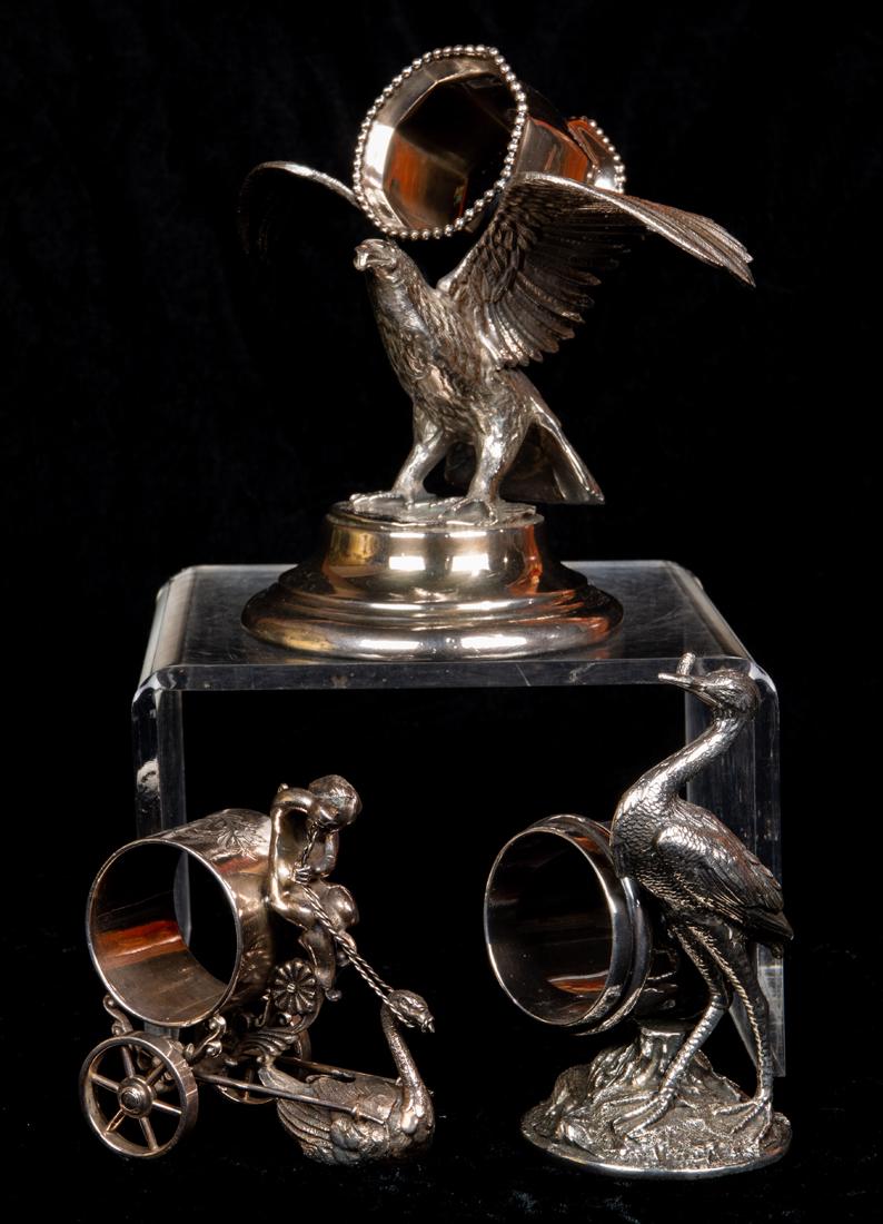(Lot of 3) Aesthetic Movement quadruple plate bird: (Lot of 3) Aesthetic Movement quadruple plate figural napkin rings featuring birds, including a heron with a fish in its mouth; a raven with windswept wings supporting an octagonal shaped ring #15 and