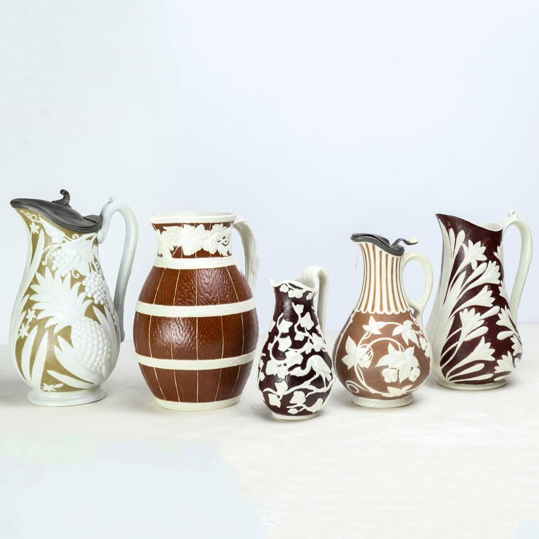 (lot of 5) American or English relief decorated parian: (lot of 5) American or English relief decorated parian ware pitchers, 19th century, comprising (2) pitchers with pewter covers, 9"h (greatest); W.R. Cobridge barrel form pitcher, relief mark circle ma