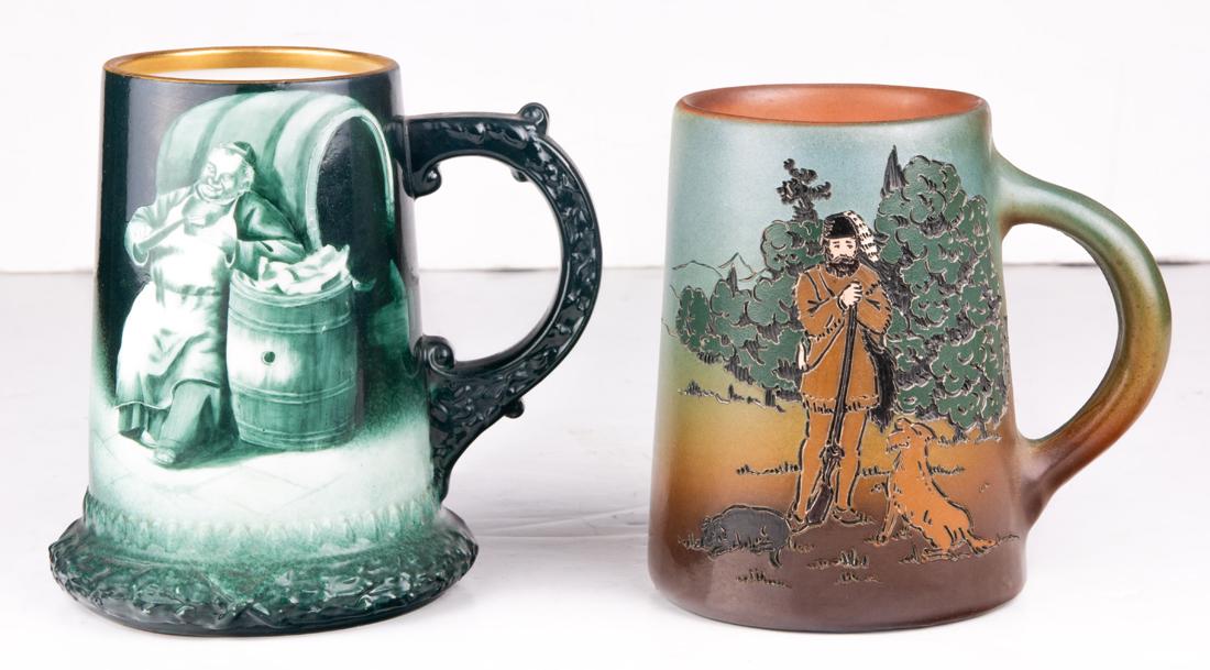 (Lot of 2) Steins, including a Dickens Ware Weller mug: (Lot of 2) Steins, including a Dickens Ware Weller mug depicting a hunter and his dog #562 together with a green sepia painted Lenox mug depicting a drunk monk in front of a keg, the taller 5.75"h