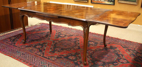 Louis XV style draw leaf table: Louis XV style draw leaf table, having a marquetry top above the scalloped apron and rising on relief carved cabriole legs, 30''h x 60''w (102''w extended) 37.5''d