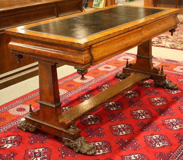 Oak library table: Late Victorian oak library table circa 1890, having a rectangular top with the original embossed gilt leather writing surface, above the ogee form apron having two blind drawers and rising on a trestl