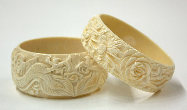 Chinese Ivory Bangle Bracelets: (lot of 2) Chinese carved ivory bangle bracelets, the first carved with leafy rosette sprigs in relief; the second rendered with a pair of writing dragons in pursuit of a jewel, overall: 3''dia, inner