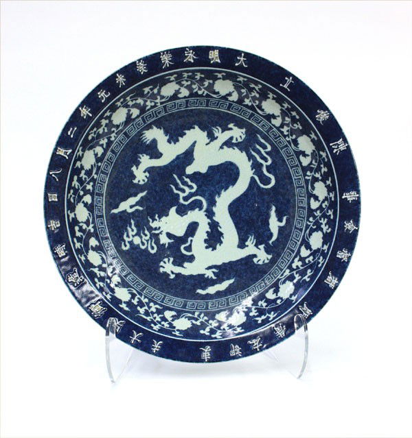 Chinese Ming-style Blue-and-White Charger: Chinese Ming-style underglaze blue decorated large porcelain dish, the well centered by a white dragon with incised details in pursuit of a jewel all set against a mottled blue cobalt ground, encircle