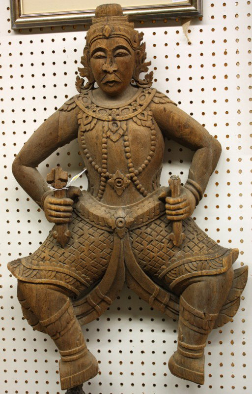 Thai Large Wood Guardian Figure: Thai large carved wood guardian figure, portrayed in a frontal pose with his legs bent and holding arrow-like weapons in each hand, the robust figure with an elaborate headdress and wearing multiple s
